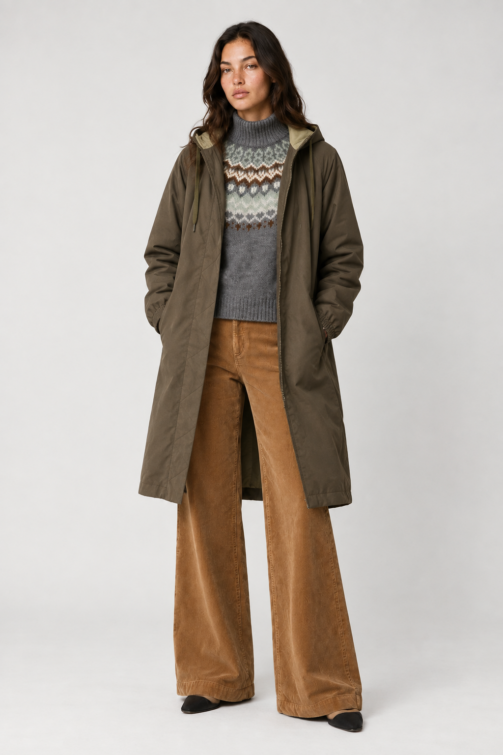 Model in grey patterned jumper, open khaki coat and tan corduroy flares